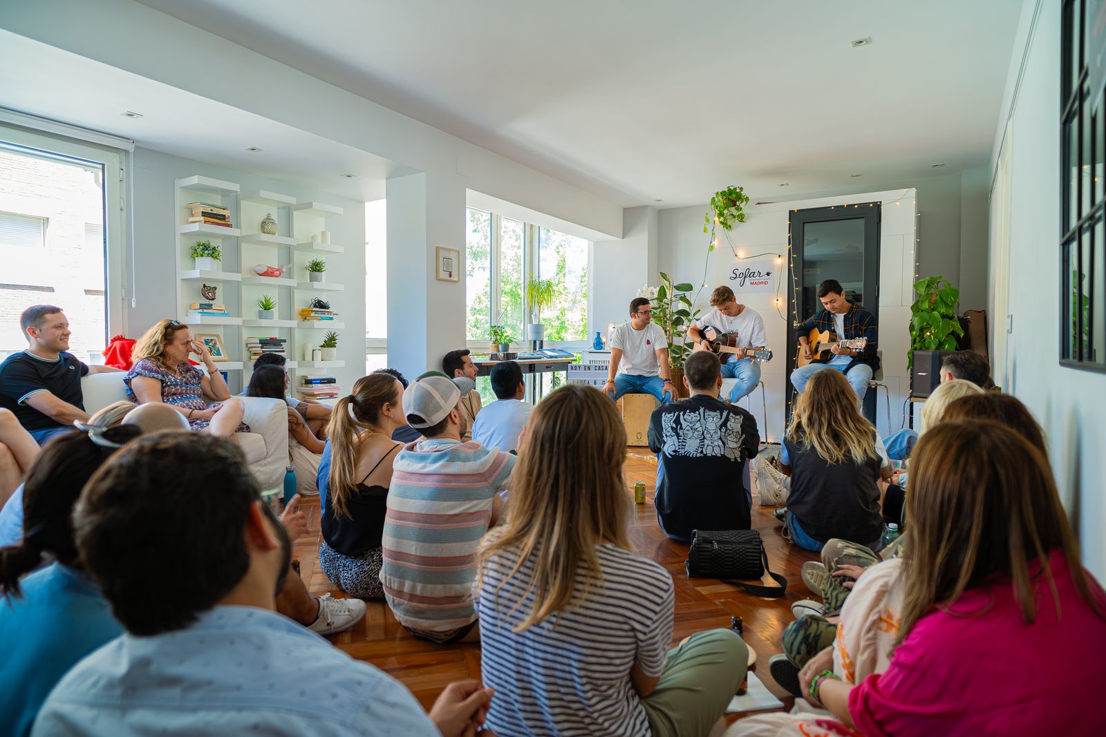 Young musicians play guitars for a small seated audience at an intimate live showcase
