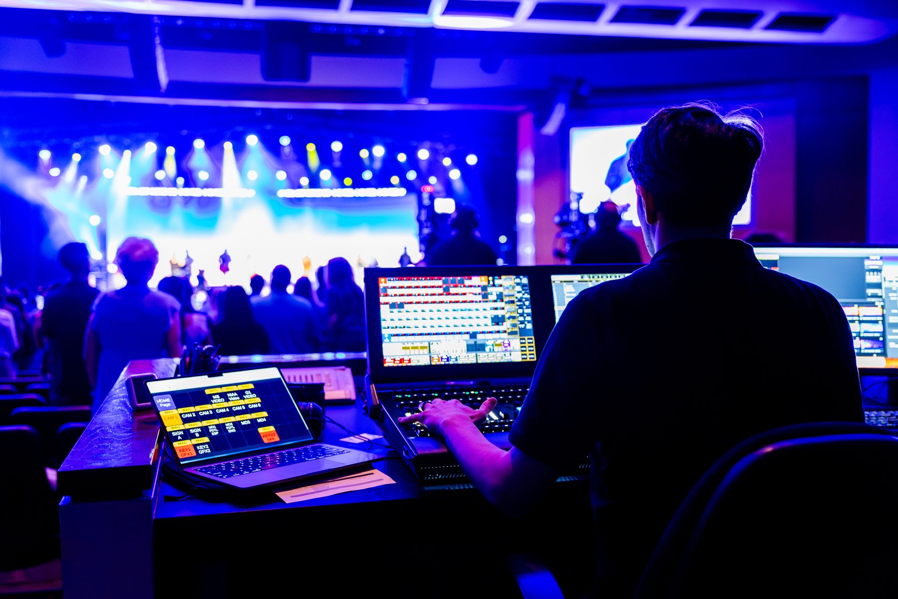 A live-event technician working at a lighting and sound control position