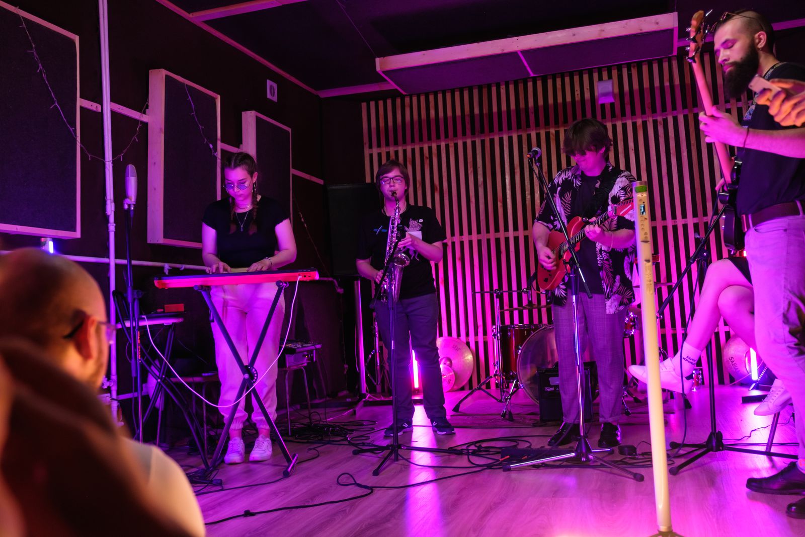 A band performing to a small audience on an indoor stage