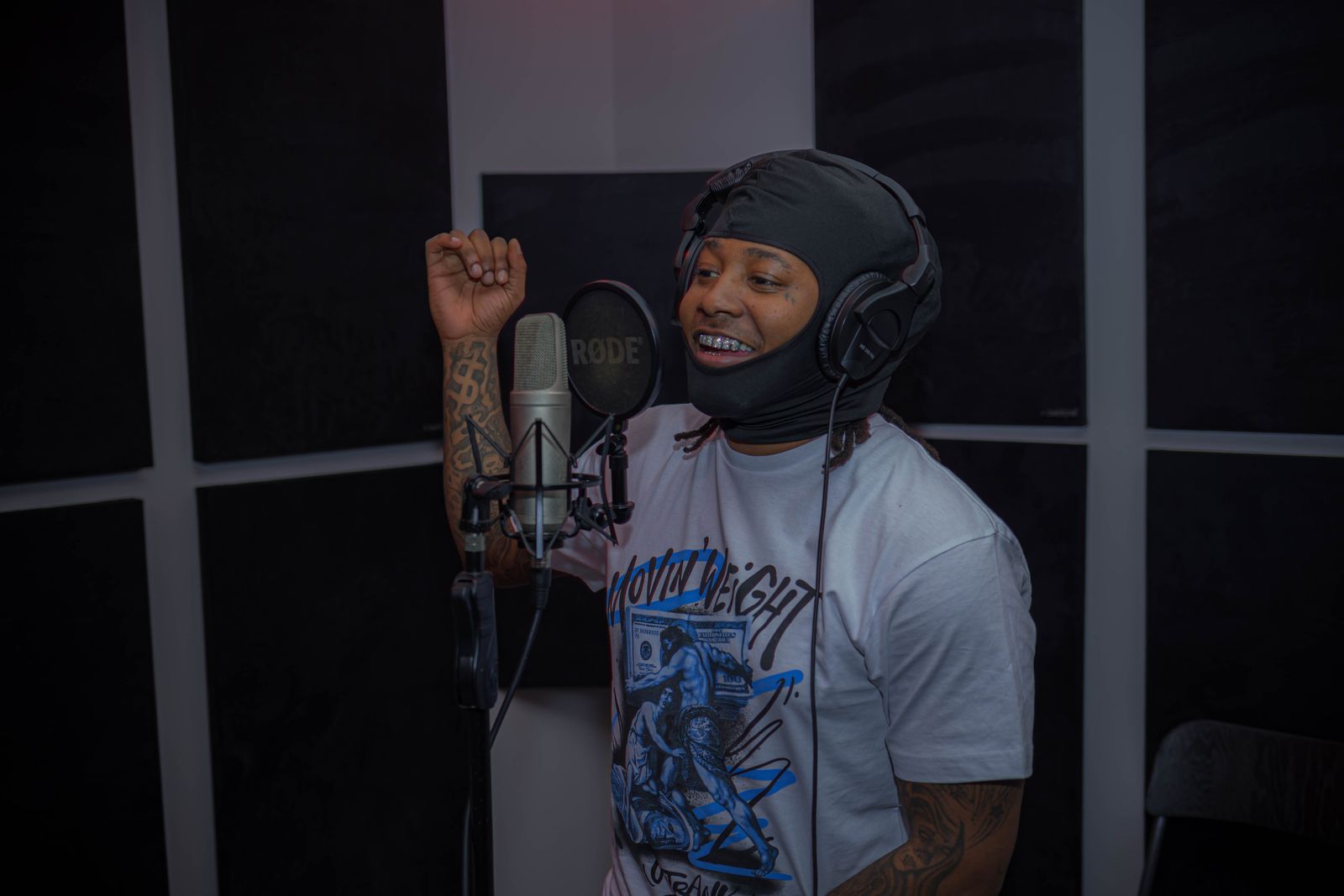 A rapper recording vocals beside a studio microphone