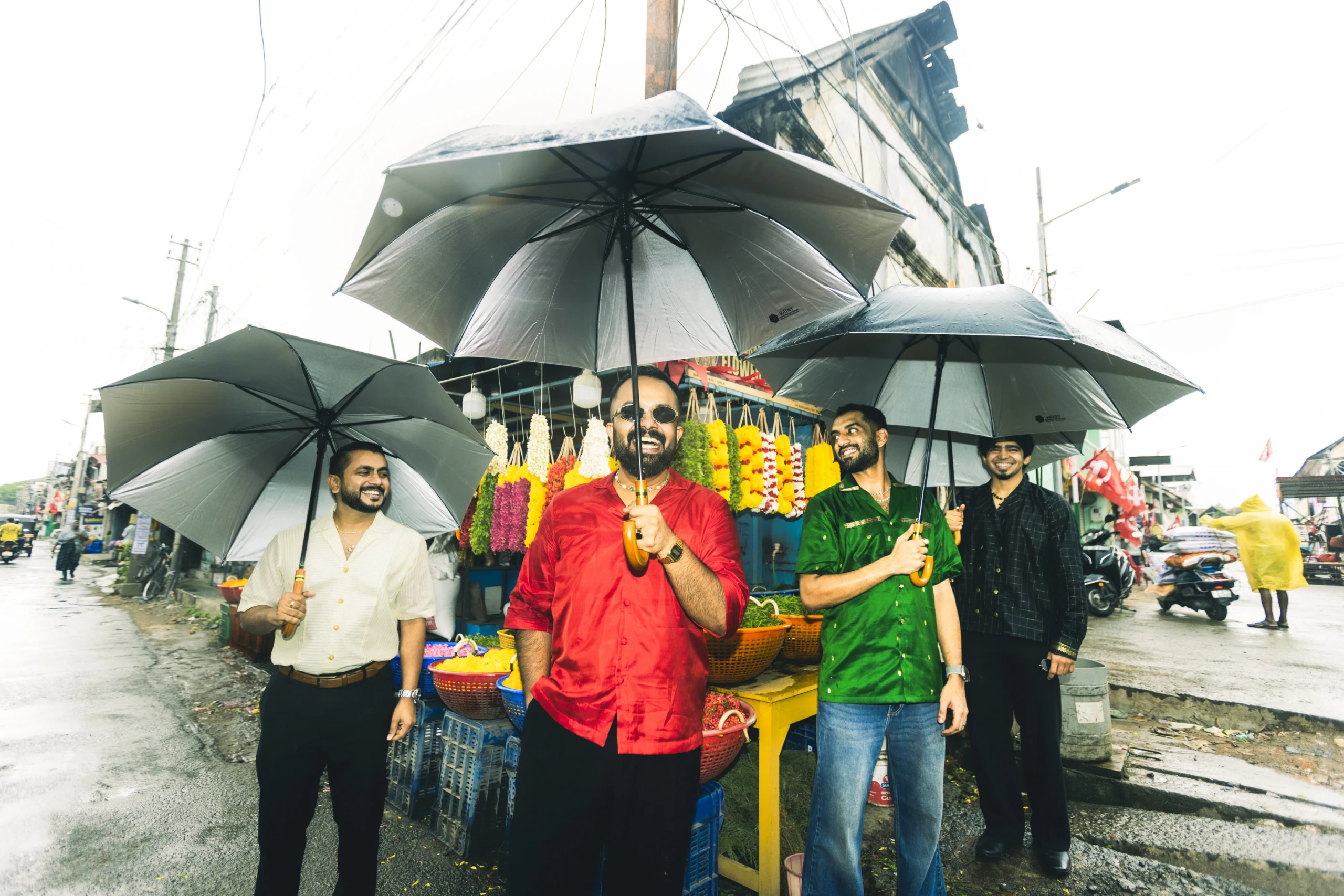 The four members of When Chai Met Toast standing under umbrellas on a rainy Kerala street